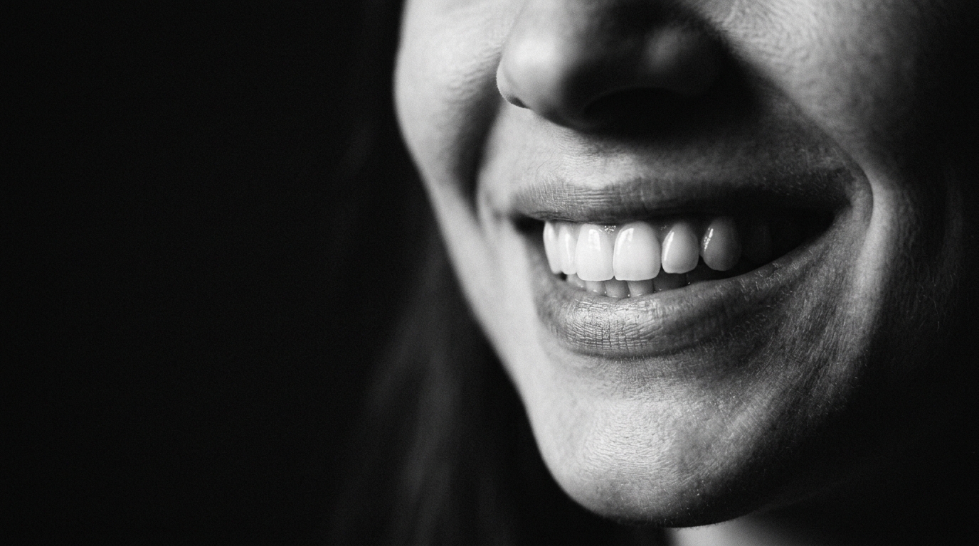 Wide monochrome macro of a smile, chin-to-nose crop against black. AI-generated demonstration, not real patients.